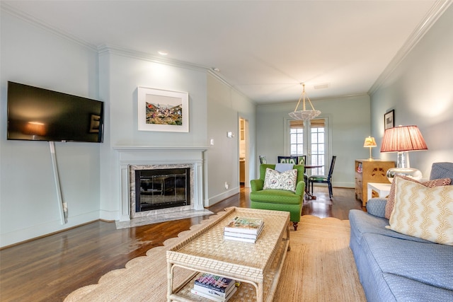 living room featuring baseboards, a premium fireplace, ornamental molding, and wood finished floors