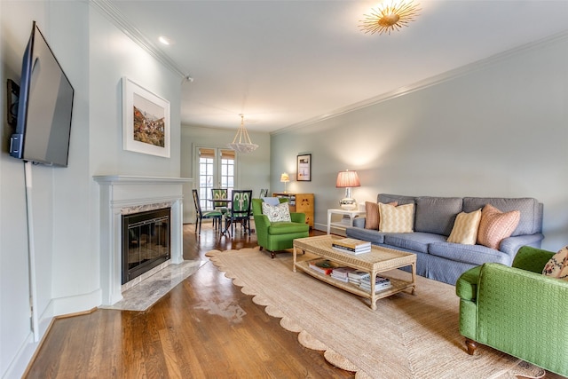 living room with ornamental molding, a high end fireplace, baseboards, and wood finished floors