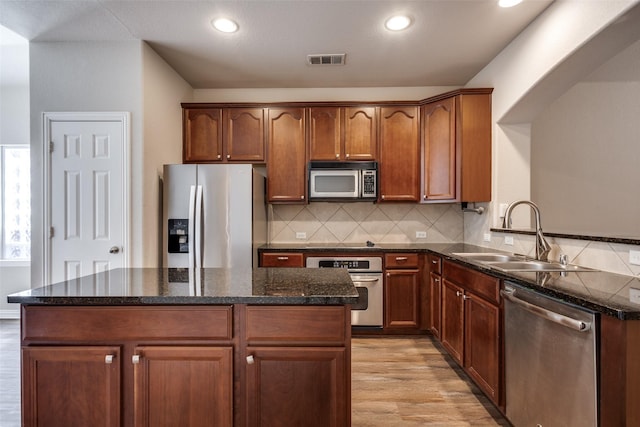 kitchen with light wood finished floors, tasteful backsplash, visible vents, appliances with stainless steel finishes, and a sink