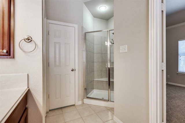 bathroom with baseboards, a shower stall, vanity, and tile patterned floors