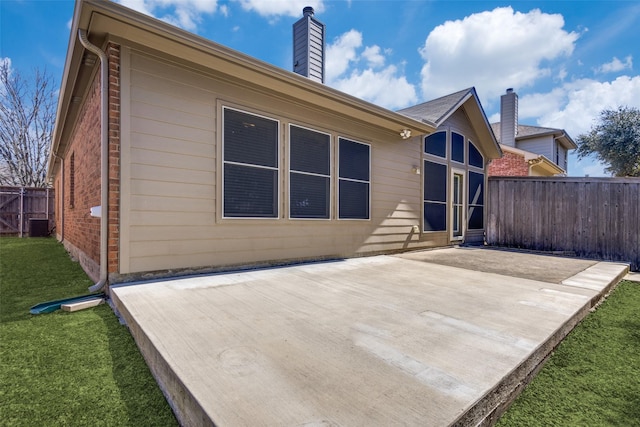 back of property featuring a yard, a patio area, fence, and brick siding