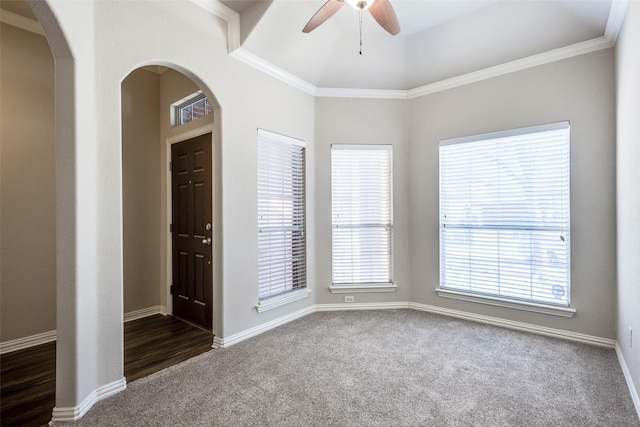 spare room featuring arched walkways, dark carpet, and crown molding