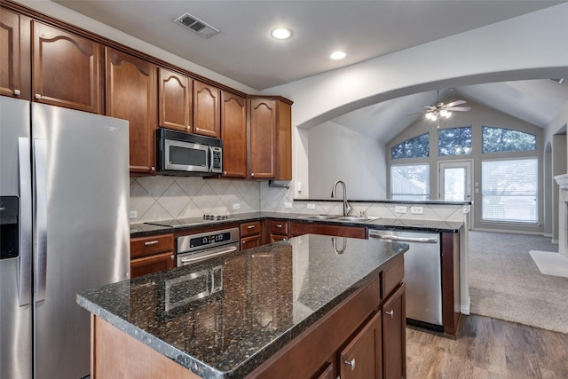 kitchen featuring visible vents, decorative backsplash, lofted ceiling, appliances with stainless steel finishes, and a sink