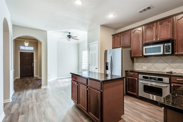 kitchen featuring visible vents, decorative backsplash, dark stone countertops, stainless steel appliances, and light wood-style floors