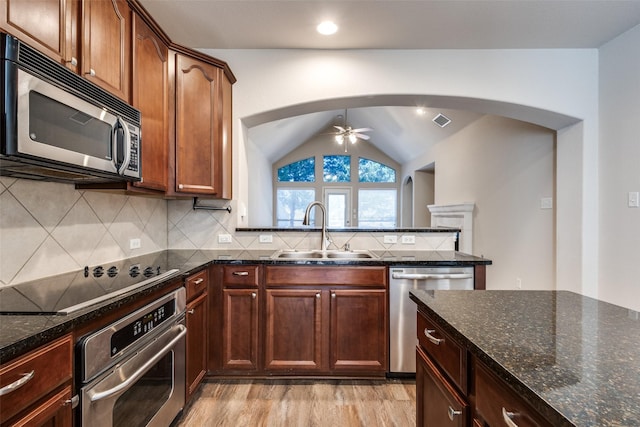 kitchen with arched walkways, decorative backsplash, appliances with stainless steel finishes, a ceiling fan, and a sink