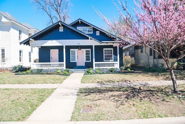 bungalow-style home with covered porch and a front yard