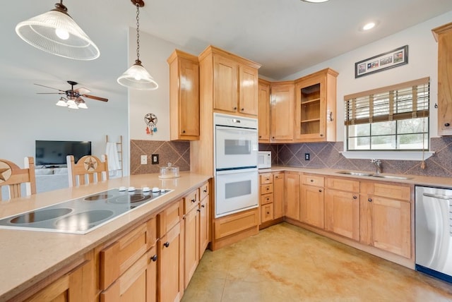 kitchen featuring white appliances, light brown cabinets, pendant lighting, and a sink