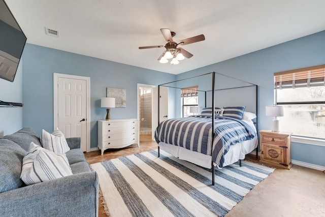 bedroom featuring ensuite bath, baseboards, visible vents, and ceiling fan