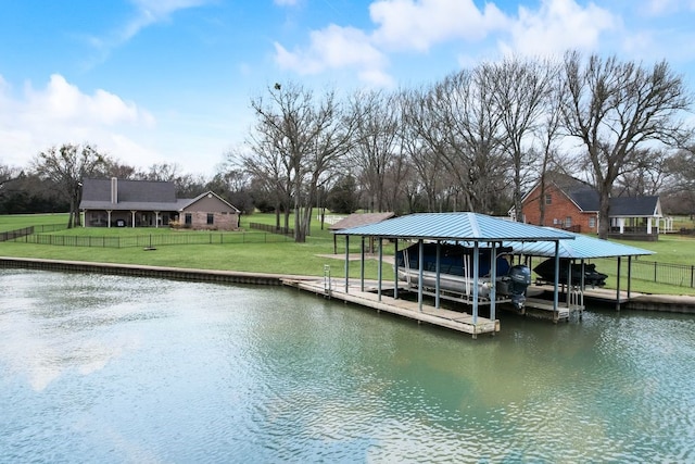 dock area with a water view, boat lift, fence, and a lawn