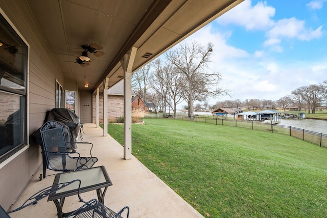 view of yard featuring visible vents, a patio, a fenced backyard, ceiling fan, and a water view