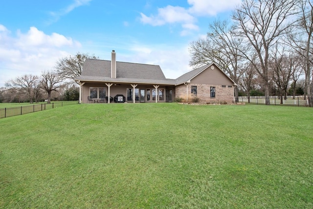 back of house featuring a yard, a chimney, and fence