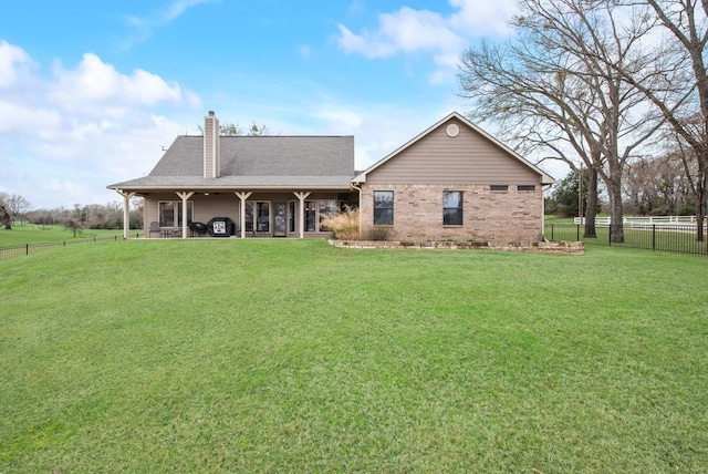 back of property with a shingled roof, a lawn, a chimney, fence, and brick siding