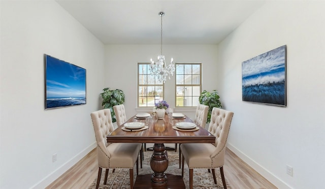 dining area featuring baseboards, light wood-style flooring, and an inviting chandelier