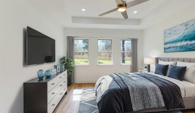 bedroom with recessed lighting, a ceiling fan, baseboards, light wood-style floors, and a raised ceiling