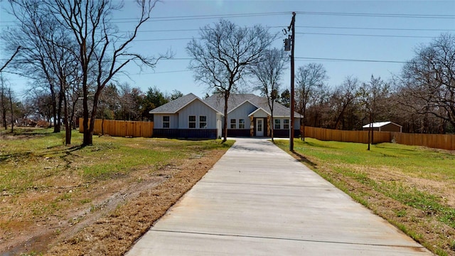 view of front of house featuring concrete driveway, a front lawn, and fence