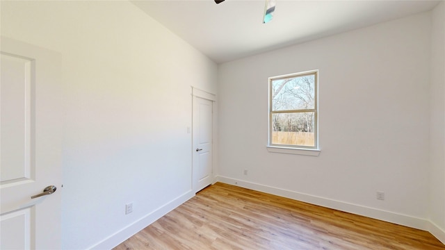 spare room featuring light wood finished floors, baseboards, and a ceiling fan