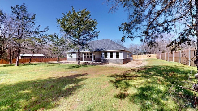 rear view of property with a fenced backyard, a lawn, and brick siding