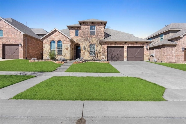 view of front of house featuring a garage, a shingled roof, concrete driveway, stone siding, and a front yard