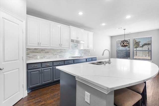 kitchen with stainless steel gas cooktop, decorative backsplash, white cabinetry, a sink, and under cabinet range hood