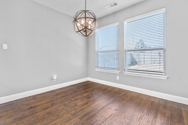 spare room with an inviting chandelier, baseboards, dark wood-style floors, and visible vents