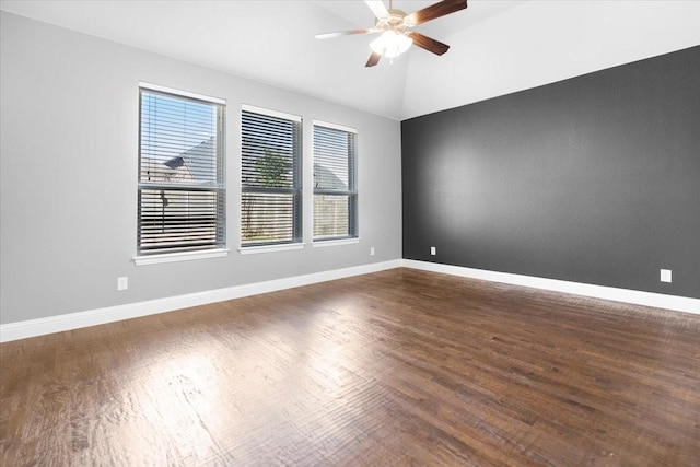 empty room featuring lofted ceiling, wood finished floors, a ceiling fan, and baseboards