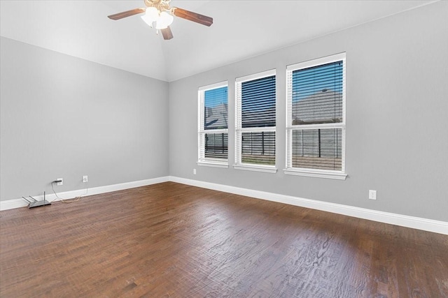 empty room featuring ceiling fan, vaulted ceiling, wood finished floors, and baseboards