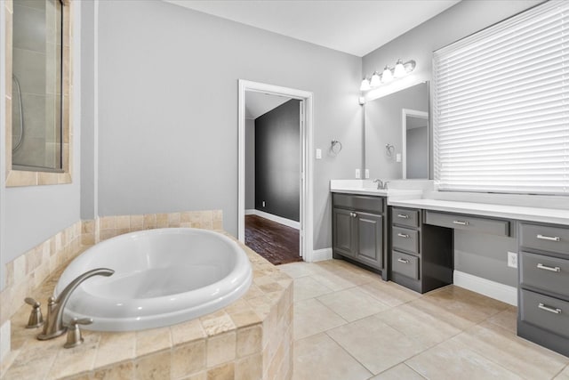 bathroom featuring tile patterned flooring, a garden tub, vanity, and baseboards