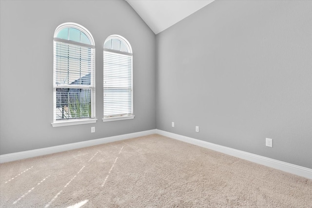 carpeted spare room with lofted ceiling and baseboards