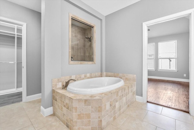 bathroom featuring a garden tub, baseboards, a tile shower, tile patterned floors, and a walk in closet