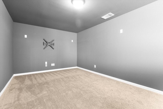 empty room with carpet, visible vents, and baseboards