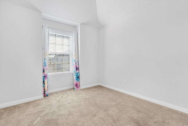 carpeted empty room featuring lofted ceiling and baseboards