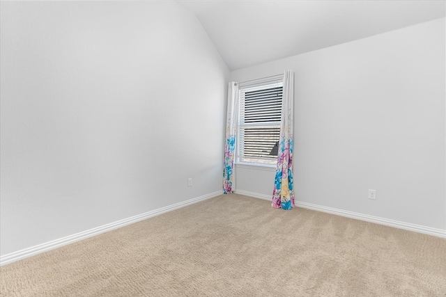 unfurnished room with light carpet, baseboards, and vaulted ceiling