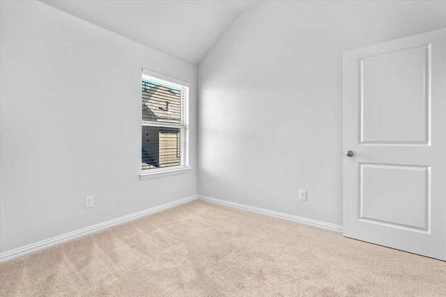 spare room featuring carpet, baseboards, and vaulted ceiling