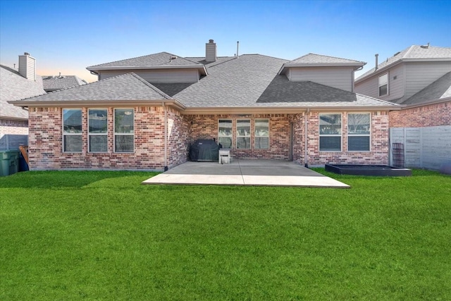 back of property featuring a yard, roof with shingles, and a patio