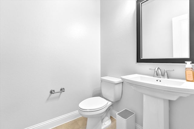 bathroom with tile patterned flooring, baseboards, a sink, and toilet