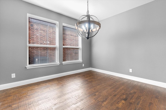 empty room with baseboards, dark wood finished floors, and an inviting chandelier