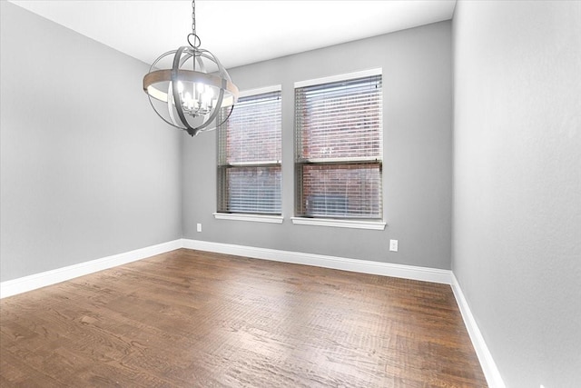 unfurnished room featuring an inviting chandelier, dark wood-style floors, and baseboards