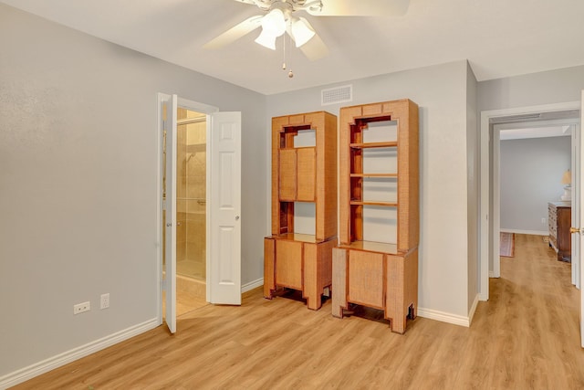 unfurnished bedroom featuring baseboards, visible vents, ensuite bath, ceiling fan, and light wood-style floors