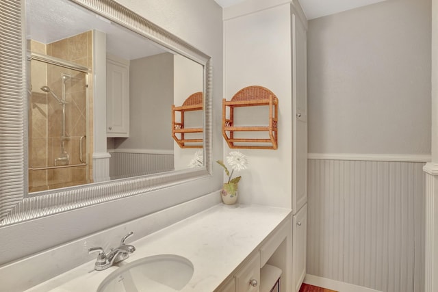 full bathroom featuring a wainscoted wall, a shower stall, and vanity