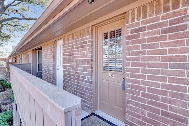 doorway to property featuring brick siding and fence