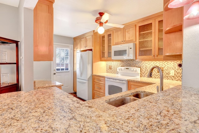 kitchen featuring white appliances, backsplash, a sink, and light stone counters