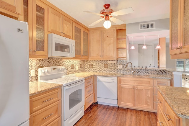 kitchen with white appliances, light brown cabinets, visible vents, and a sink