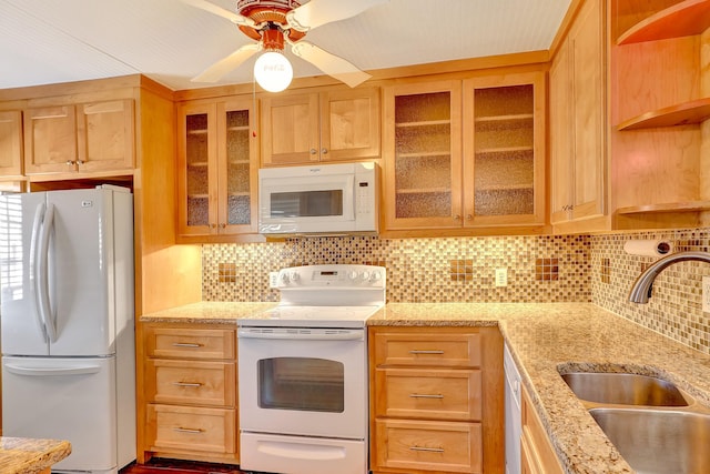 kitchen with white appliances, a sink, light stone countertops, and decorative backsplash