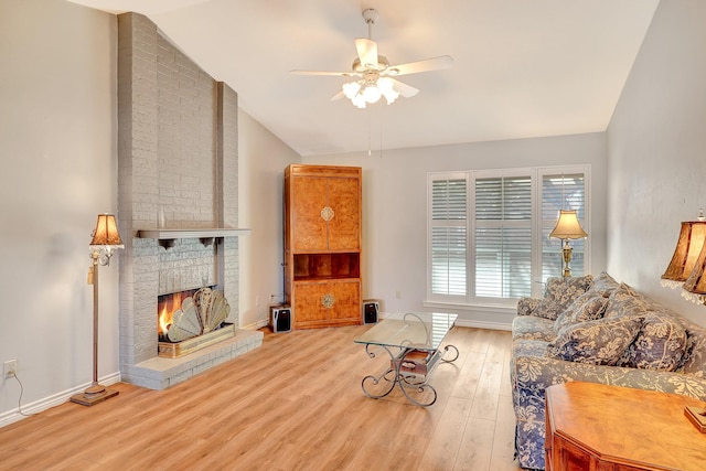 living area with a brick fireplace, ceiling fan, vaulted ceiling, wood finished floors, and baseboards