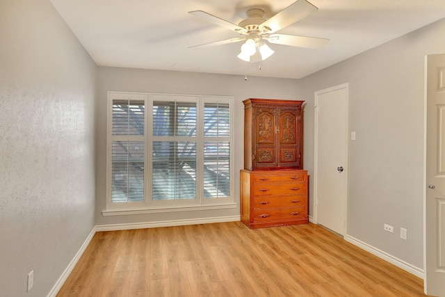 spare room with ceiling fan, light wood finished floors, and baseboards