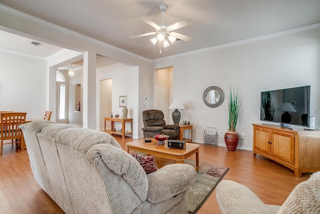 living area with light wood-type flooring, ceiling fan, visible vents, and ornamental molding