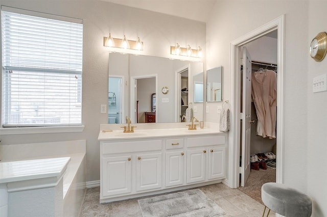 full bathroom with double vanity, a walk in closet, a sink, and tile patterned floors