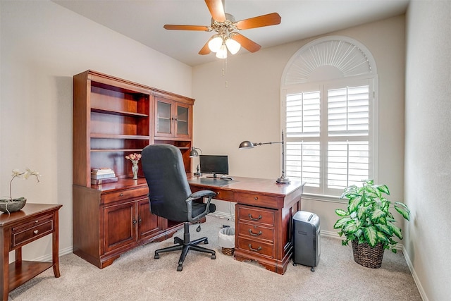 office featuring a ceiling fan, light colored carpet, and baseboards