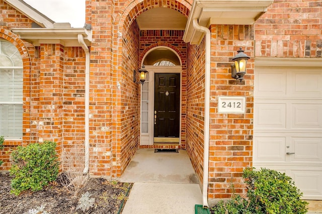 doorway to property with brick siding and an attached garage