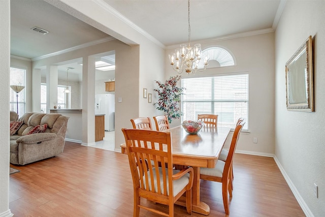 dining room with baseboards, visible vents, crown molding, light wood-type flooring, and a chandelier